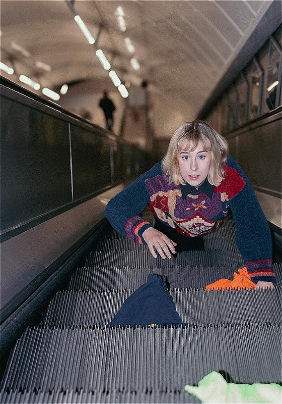A woman climbs up an escalator on her hands and knees.