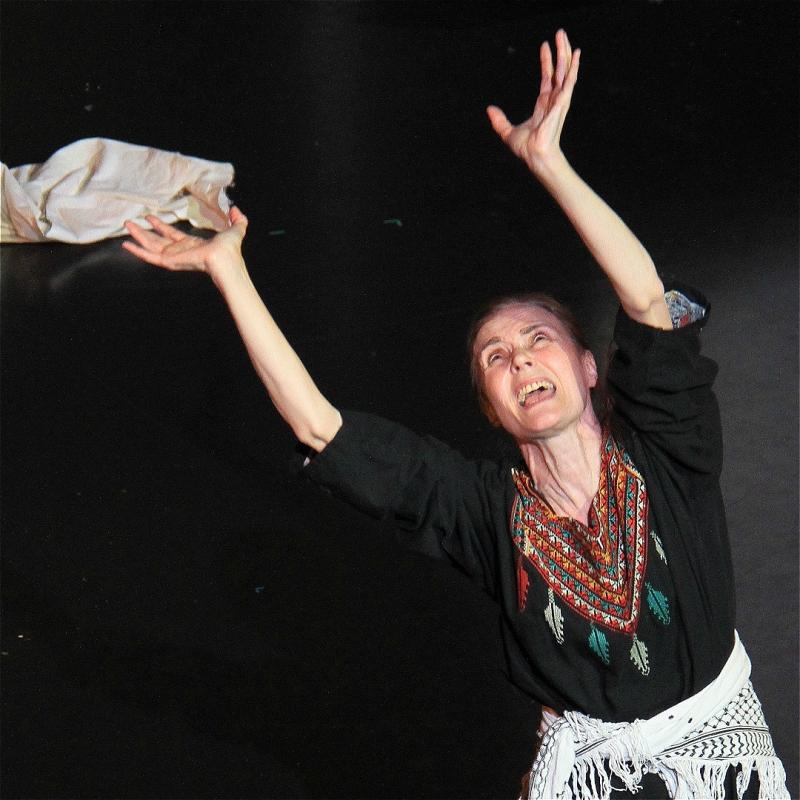 The performer is on stage, looking upwards with their hands in the air. 